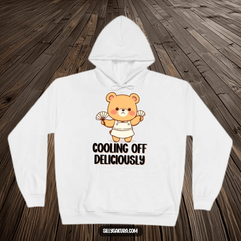 Funny Hoodie depicting a tiny bear chef in a cute apron, energetically fanning themselves with a fan, looking slightly warm but happy.